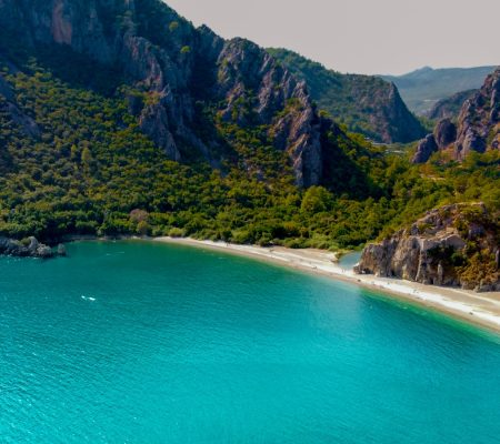 green and brown mountain beside blue sea during daytime