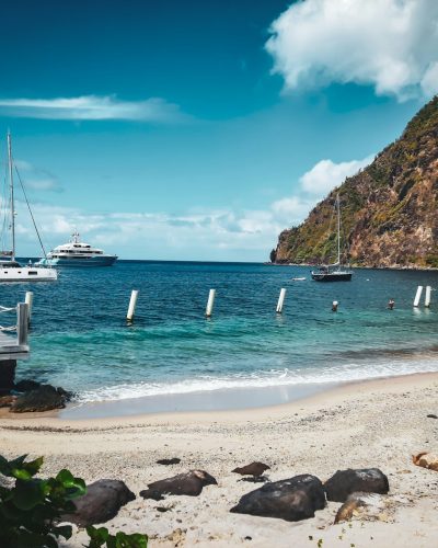a beach with boats in the water and a mountain in the background